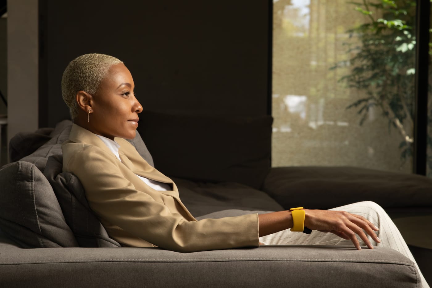 A woman wearing the TapXR wristband, sitting in a sunlit living room